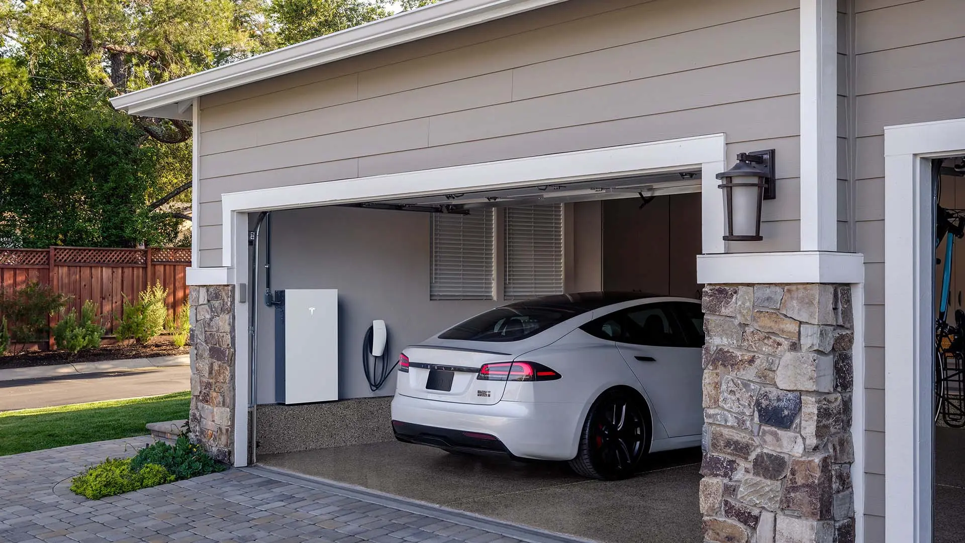 Tesla Powerwall and Wall Connector in a garage with a Tesla car